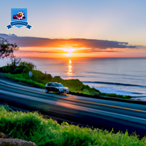 An image of a vibrant sunset over the Pacific Ocean in Ocean View, Hawaii, with a car driving along the scenic coastal road, symbolizing affordable auto insurance options in the area